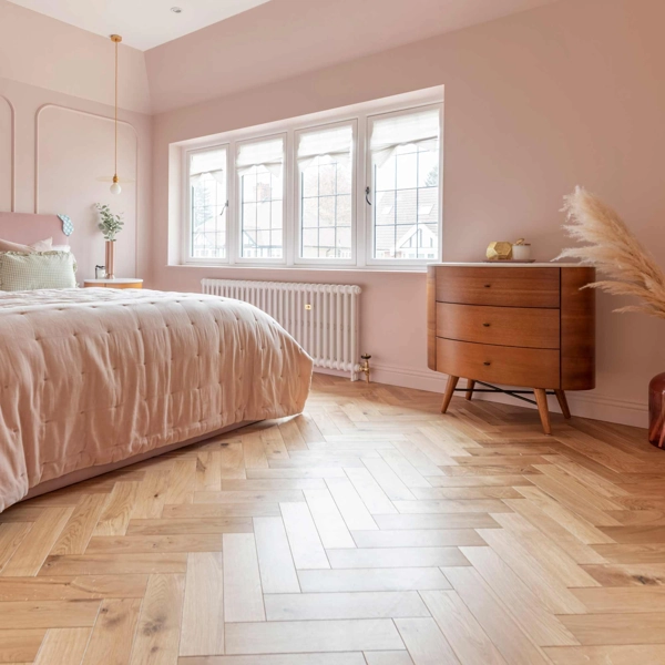 Pink bedroom with light herringbone wood floors