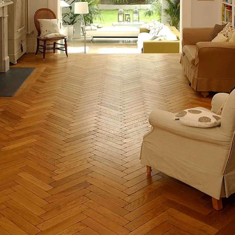 Warm-toned herringbone wood flooring in a furnished living room.