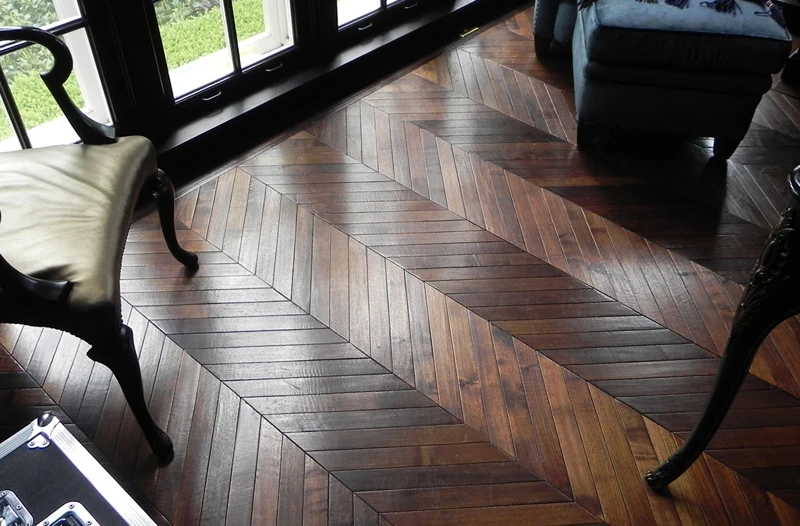 dark-stained wooden floor featuring a V-shaped chevron parquet pattern.