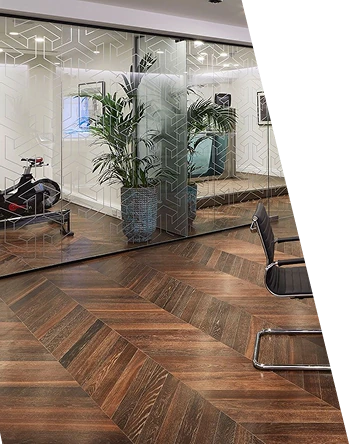 Dark chevron wood flooring in an office with a glass partition.