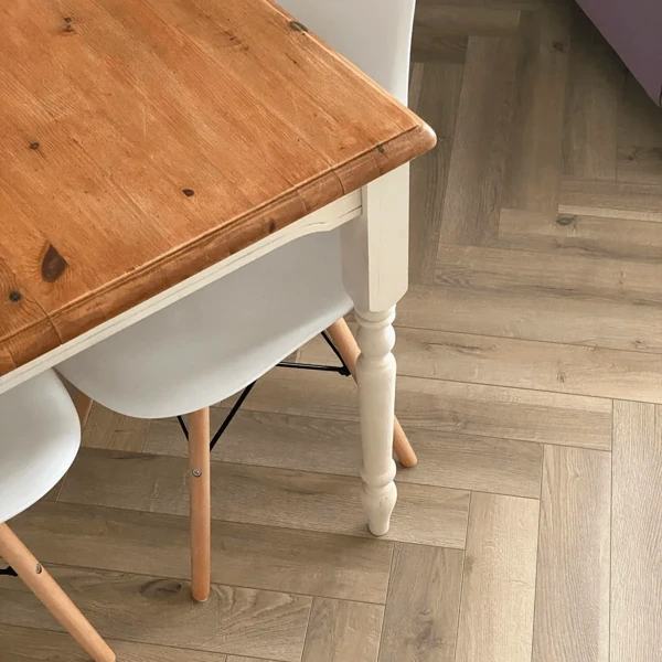 Brown laminate herringbone parquet flooring next to a dining table